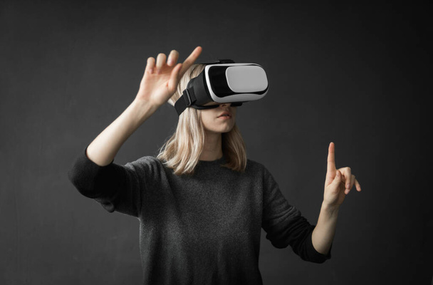 Young woman wearing virtual reality goggles headset, vr box. Connection, technology, new generation, progress concept. Girl trying to touch objects in virtual reality. - Fotografie, Obrázek