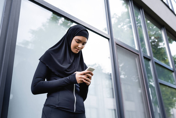 vista basso angolo di giovane donna musulmana utilizzando smartphone  - Foto, immagini