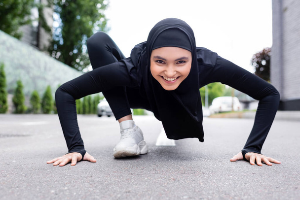 deportista árabe feliz en hijab ejercicio sobre asfalto
  - Foto, Imagen