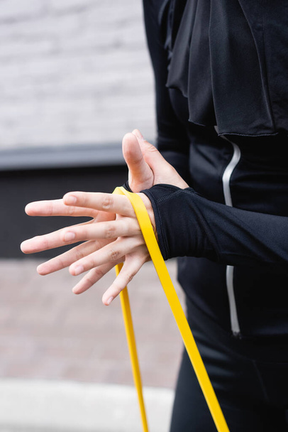 cropped view of sportswoman exercising with resistance band - Photo, Image