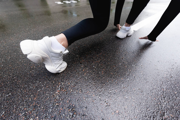 vista recortada de la mujer en zapatillas blancas de pie en posición inicial fuera
  - Foto, Imagen