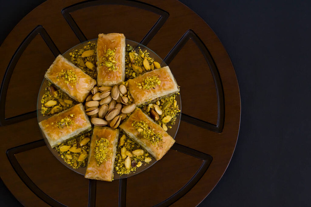 Traditional Turkish Pastry Dessert,Pistachio Baklava on wooden plate with pistachio nuts - Fotó, kép