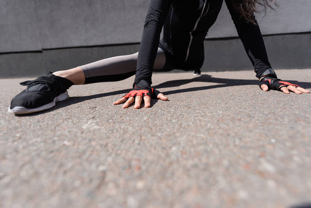 cropped view of young sportswoman stretching on asphalt - Photo, Image