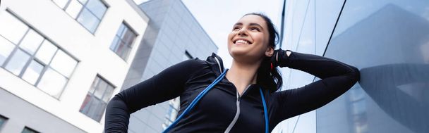 panoramic orientation of happy sportswoman with skipping rope smiling outside  - Fotoğraf, Görsel