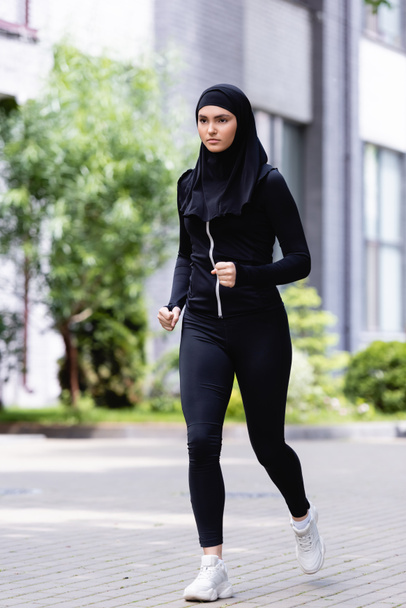 young arabian sportswoman in hijab and sportswear running outside  - Photo, Image