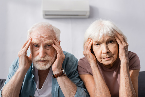 Yaşlı çift evde sıcaktan acı çekerken kameraya bakıyor.  - Fotoğraf, Görsel