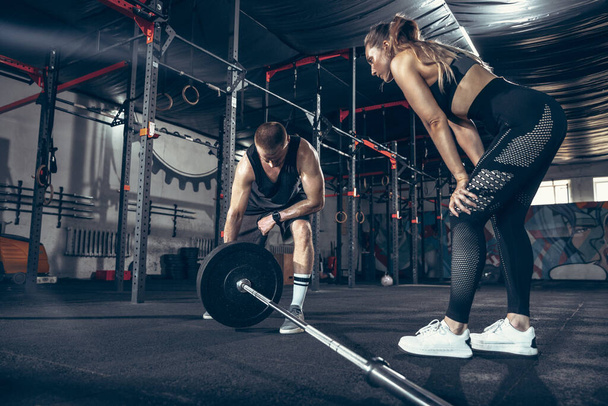 Beautiful young sporty couple training, workout in gym together - Zdjęcie, obraz