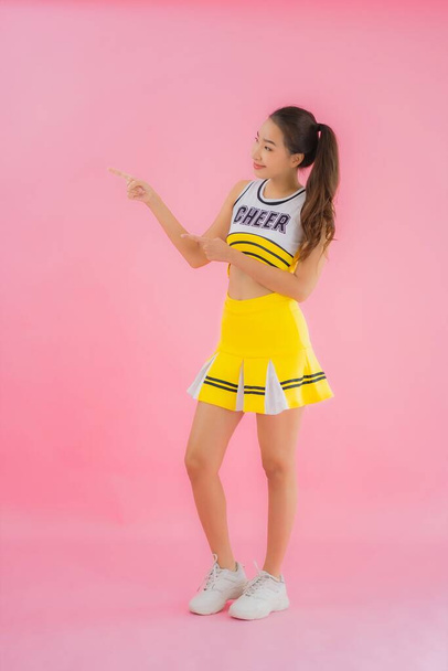 Portrait beautiful young asian woman cheerleader on pink isolated background - Fotó, kép