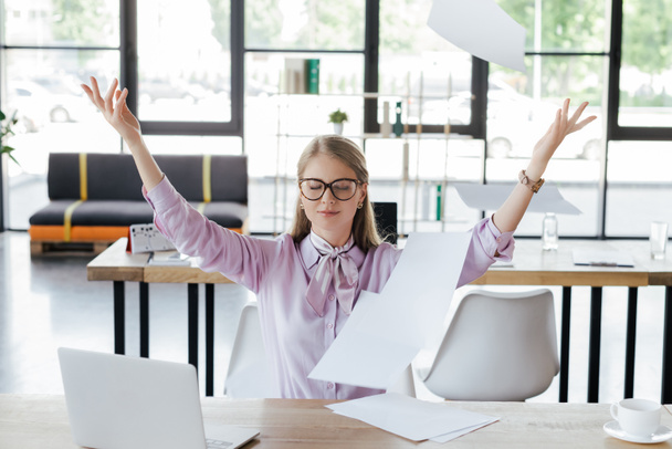 beautiful businesswoman in glasses throwing in air documents in office  - Foto, immagini