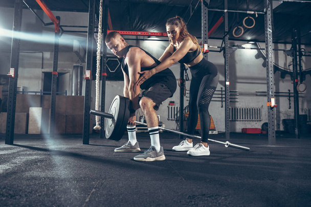 Beautiful young sporty couple training, workout in gym together - Foto, Bild