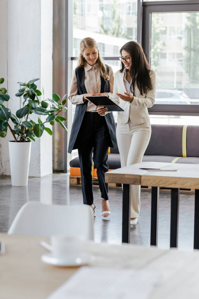 selective focus of beautiful businesswomen smiling and looking at clipboard  - Фото, зображення