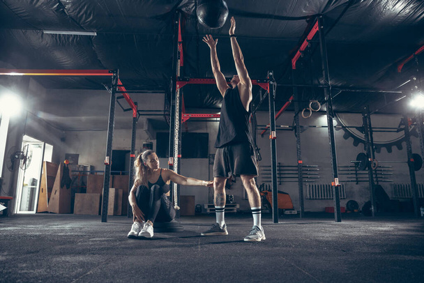 Beautiful young sporty couple training, workout in gym together - 写真・画像
