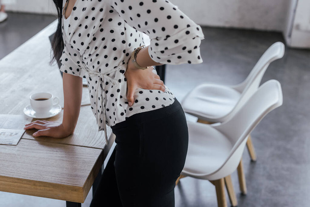 cropped view of businesswoman touching back while suffering from pain in office - Фото, зображення