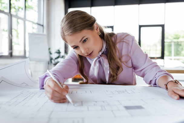 selective focus of attractive businesswoman drawing blueprints in office - Zdjęcie, obraz