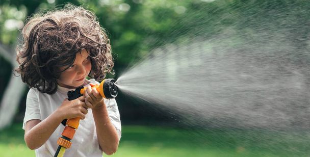 child plays with water in the backyard in the garden - Foto, immagini