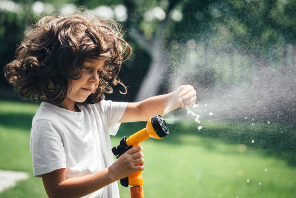 child plays with water in the backyard in the garden - Foto, Imagem