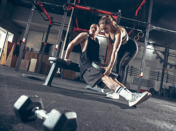 Beautiful young sporty couple training, workout in gym together - Foto, Imagem