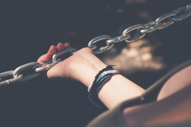 Woman hand holding onto a stainless steel chain. Woman's struggle conept idea - Foto, Imagem