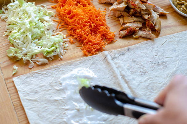 Shaurma, burrito, chicken roll in a pita with fresh vegetables and cream sauce on dark wooden background - Foto, imagen
