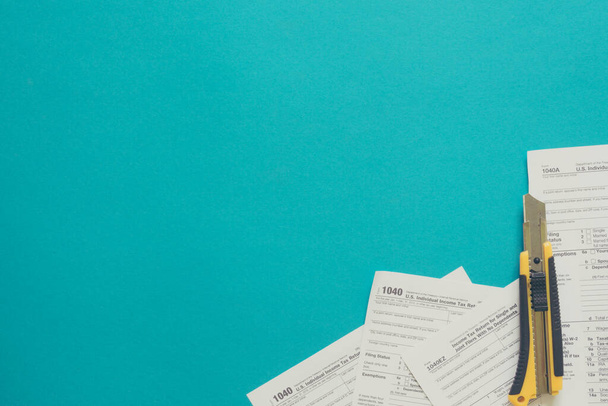 Steuerformulare mit einem Ausschnitt auf blauem Hintergrund und Kopierraum. Steuersenkungskonzept - Foto, Bild