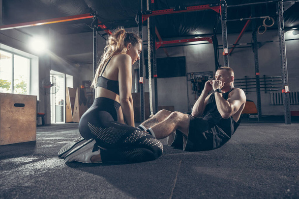 Beautiful young sporty couple training, workout in gym together - Фото, зображення