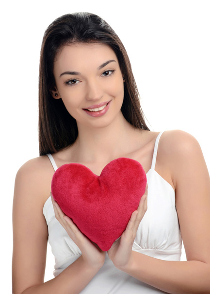 Beautiful brunette girl holding a red heart. Happy woman, Valentine day. Focus on the heart, blur on the model. - Foto, Bild