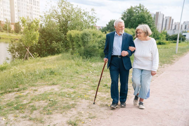 An adult European couple walks around the city. A walk in the fresh air grandparents go by the hand in urban. The concept of a happy family life - Φωτογραφία, εικόνα