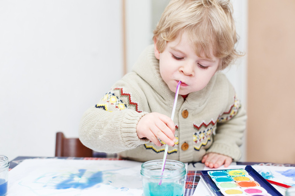 Cute toddler boy having fun indoor, painting with different pain - Photo, Image