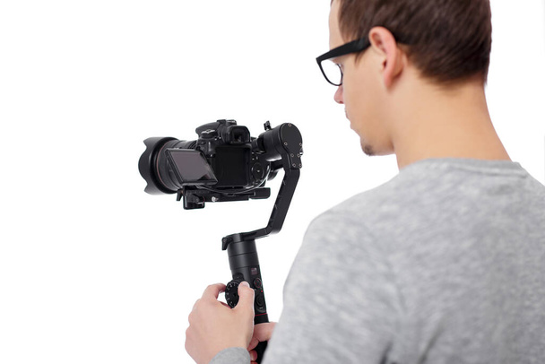 back view of professional videographer using dslr camera on gimbal stabilizer isolated on white background, focus on camera - Photo, Image
