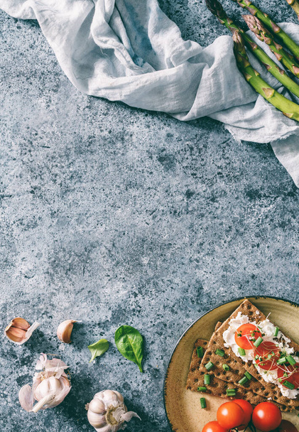 Roggenbrot Toast mit Ziegenkäse, Tomaten, Setzlingen auf Teller auf blauem Hintergrund mit Leinenserviette. Gesunde vegane Ernährung, saubere Ernährung, Diät, Draufsicht, Straffung - Foto, Bild