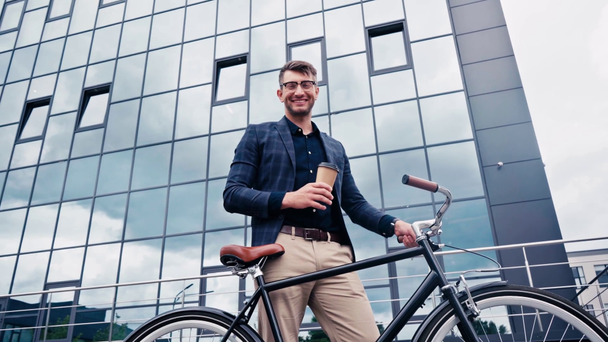ευτυχισμένος άνθρωπος κρατώντας χάρτινο κύπελλο και στέκεται με ποδήλατο έξω  - Πλάνα, βίντεο