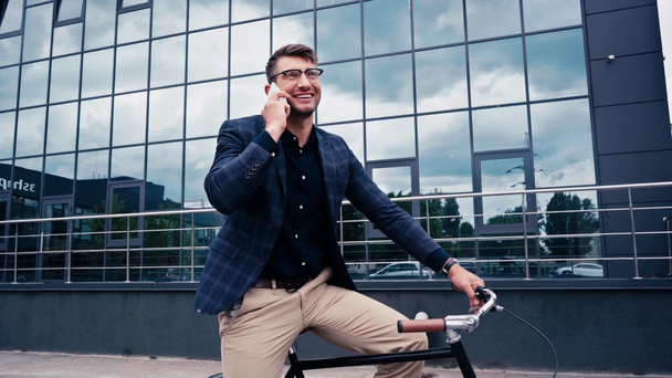 szczęśliwy człowiek mówi na smartfonie i siedzi na rowerze  - Materiał filmowy, wideo