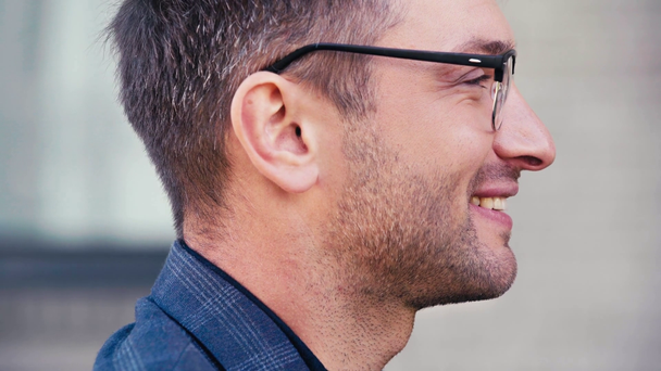 oldalnézetben jóképű férfi szemüvegben mosolyog, miközben beszél kívül - Felvétel, videó