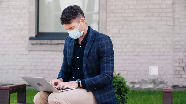 freelancer in medisch masker met behulp van laptop buiten  - Video
