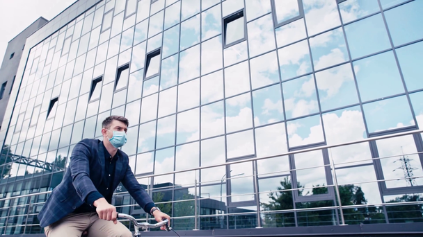 homme en masque médical équitation vélo près du bâtiment  - Séquence, vidéo