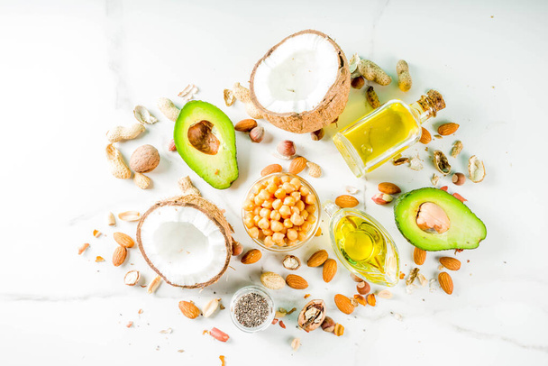 Healthy vegan fat food sources, omega3, omega6 ingredients - almond, pecan, hazelnuts, walnuts, olive oil, chia seeds, avocado, coconut, dark green background copy space - Fotó, kép