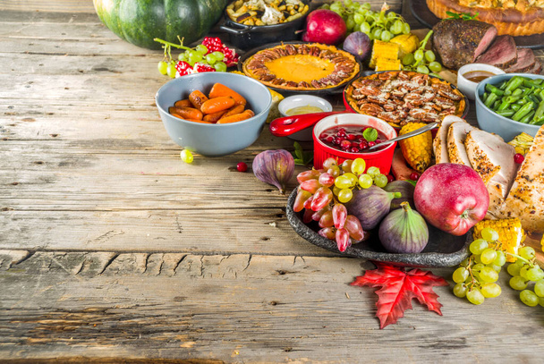 Thanksgiving family dinner setting concept. Traditional Thanksgiving day food  with turkey, green beans and mashed potatoes, stuffing, pumpkin, apple and pecan pies, rustic wooden table - Photo, Image