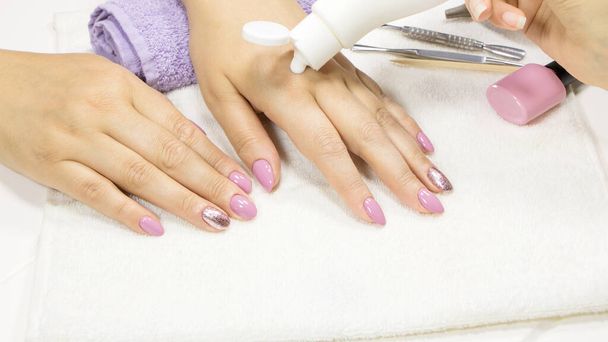 The manicurist applies a moisturizer to the client's hand. SPA manicure, procedure, moisturizing. Hand lotion, cream. Skin care. Beauty salon. Manicure concept. Beauty nails. Soft skin. Cosmetic cream - Photo, Image