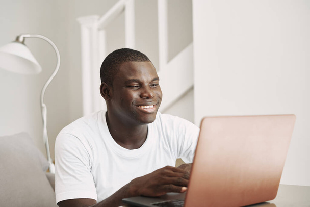 Happy man with African appearance looks at the monitor screen laptop education  - Foto, imagen