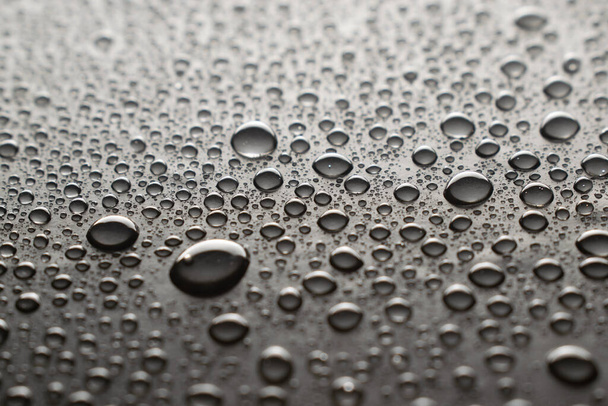 Druppels water op een donkere glazen textuur achtergrond - Foto, afbeelding