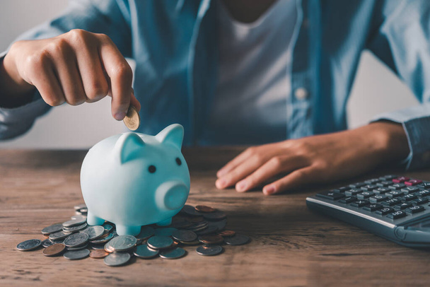   Hand holding coin with pig piggy bank. Saving and financial accounts concept - Photo, Image