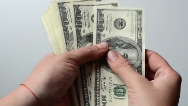 A személy 100 dollár bankjegyeket számol a kezében. Fehér háttér. Egy rakás pénz. Gazdag ember. Több ezer dollár..  - Felvétel, videó
