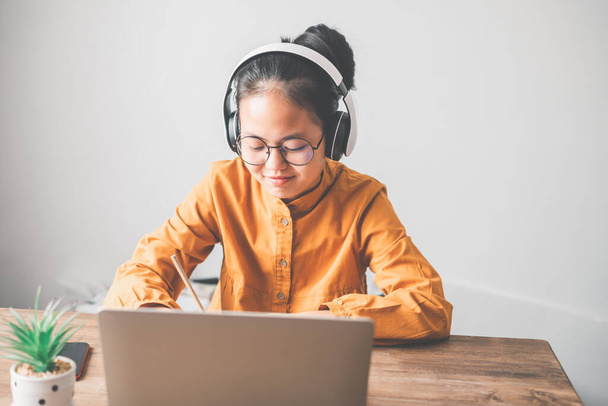 Teenage Asijské studenty ve žlutých šatech s sluchátkem komunikují prostřednictvím videokonference pro online učení. Ve videokonferenčním hovoru přes aplikace. nový normální koncept - Fotografie, Obrázek