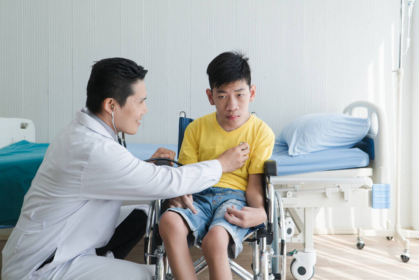 Aziatische vrijwilligers Artsen Zorgen en Helpen Revalidatie van Gehandicapten Jongens Verblijf in het ziekenhuis. De jongen is kreupel, Aziaten kunnen er niets aan doen. Moet altijd in een rolstoel zitten. - Foto, afbeelding