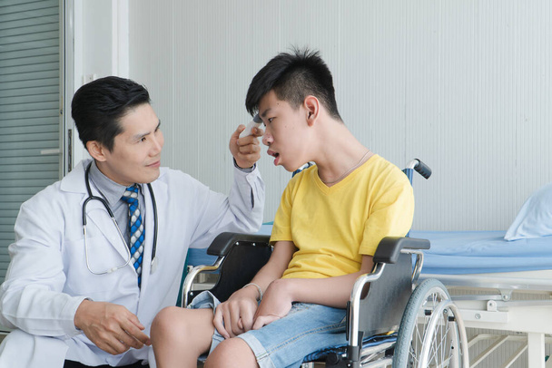 Médicos Voluntarios Asiáticos Cuidando y Ayudando a la Rehabilitación de Niños Discapacitados Permanezcan en el hospital. El chico está lisiado, los asiáticos no pueden evitarlo. Debe sentarse en una silla de ruedas todo el tiempo.
 - Foto, Imagen