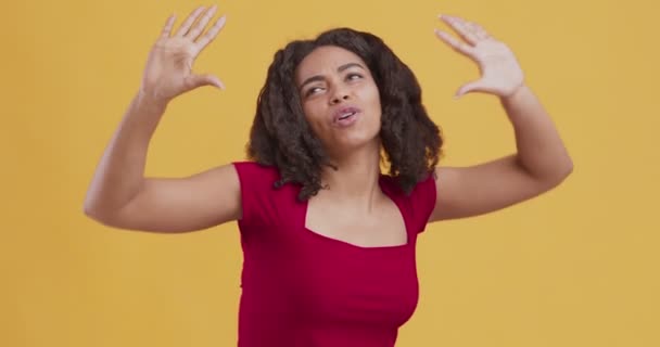 Μαύρο κορίτσι χορεύει, απολαμβάνοντας δυναμική μουσική σε πορτοκαλί φόντο - Πλάνα, βίντεο