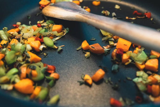 Siyah bir tavada ve tahta kaşıkta pişirilen sağlıklı sebzelere yakın çekim - Fotoğraf, Görsel