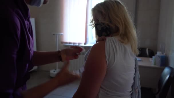 Vaccinazione durante la pandemia di coronavirus. Il medico somministra un'iniezione al paziente mascherato durante Covid-19. Vaccinazione contro la difterite. - Filmati, video