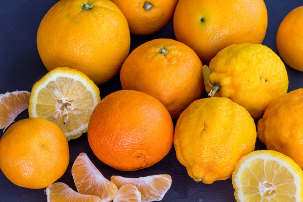 Citrus background with lemons, mandarin and oranges isolated on black background - whole and cut - Photo, Image