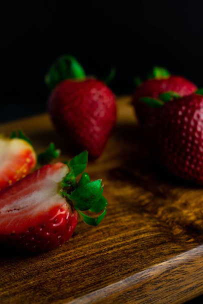 A closeup shot of fresh ripe strawberries on a wooden board - Foto, Imagem